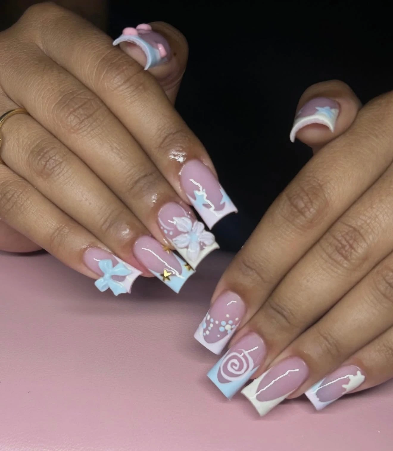 Pale blue and white nail art with raised bows, flowers and gold stars