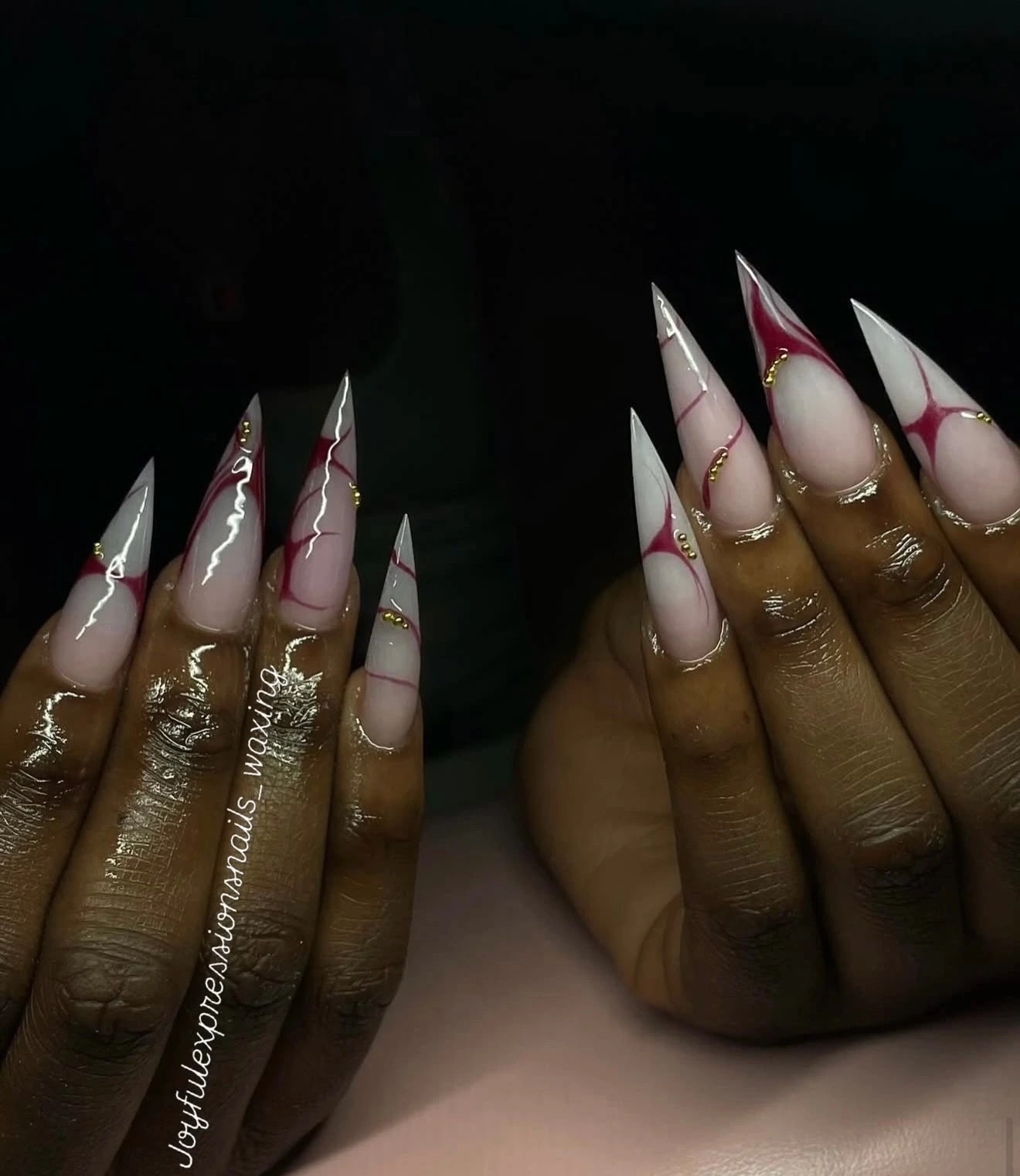 Pointed nude and burgundy stiletto nails with gold accents