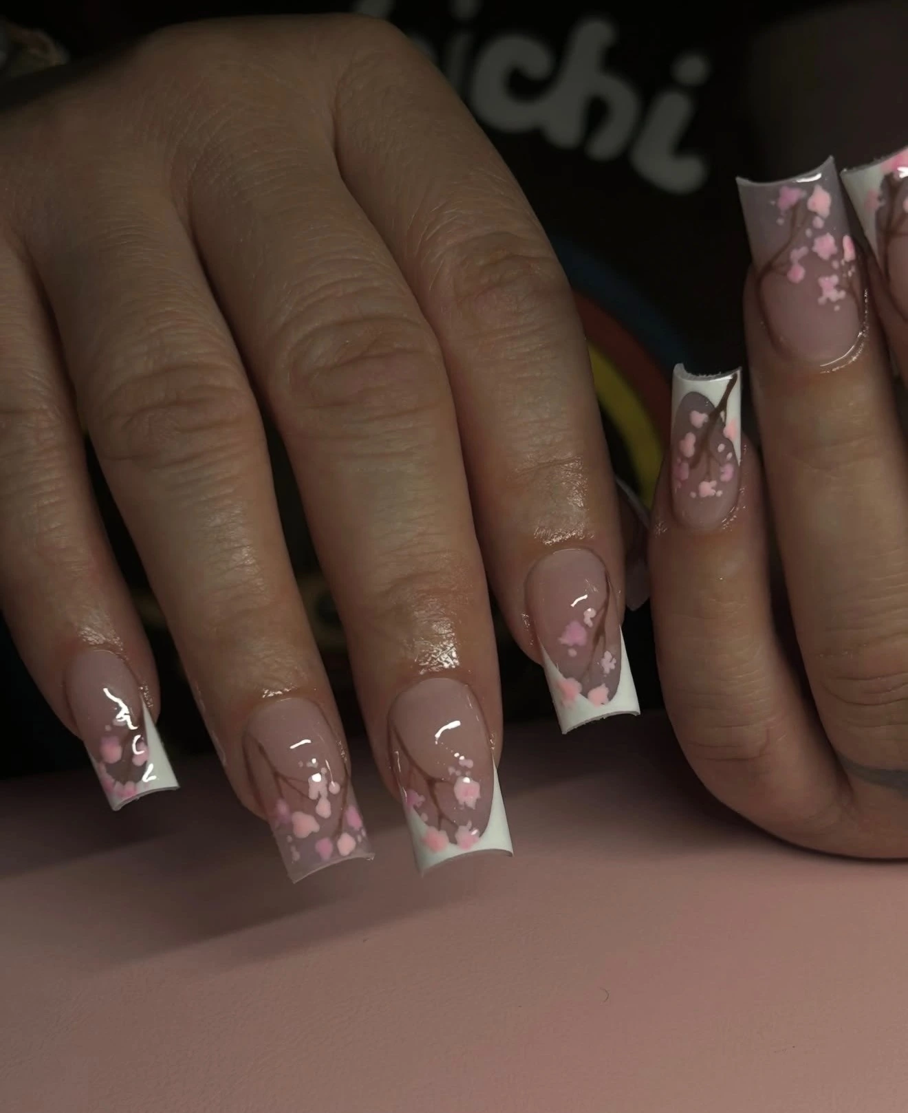 Pink blossom branches over nude and white French nails