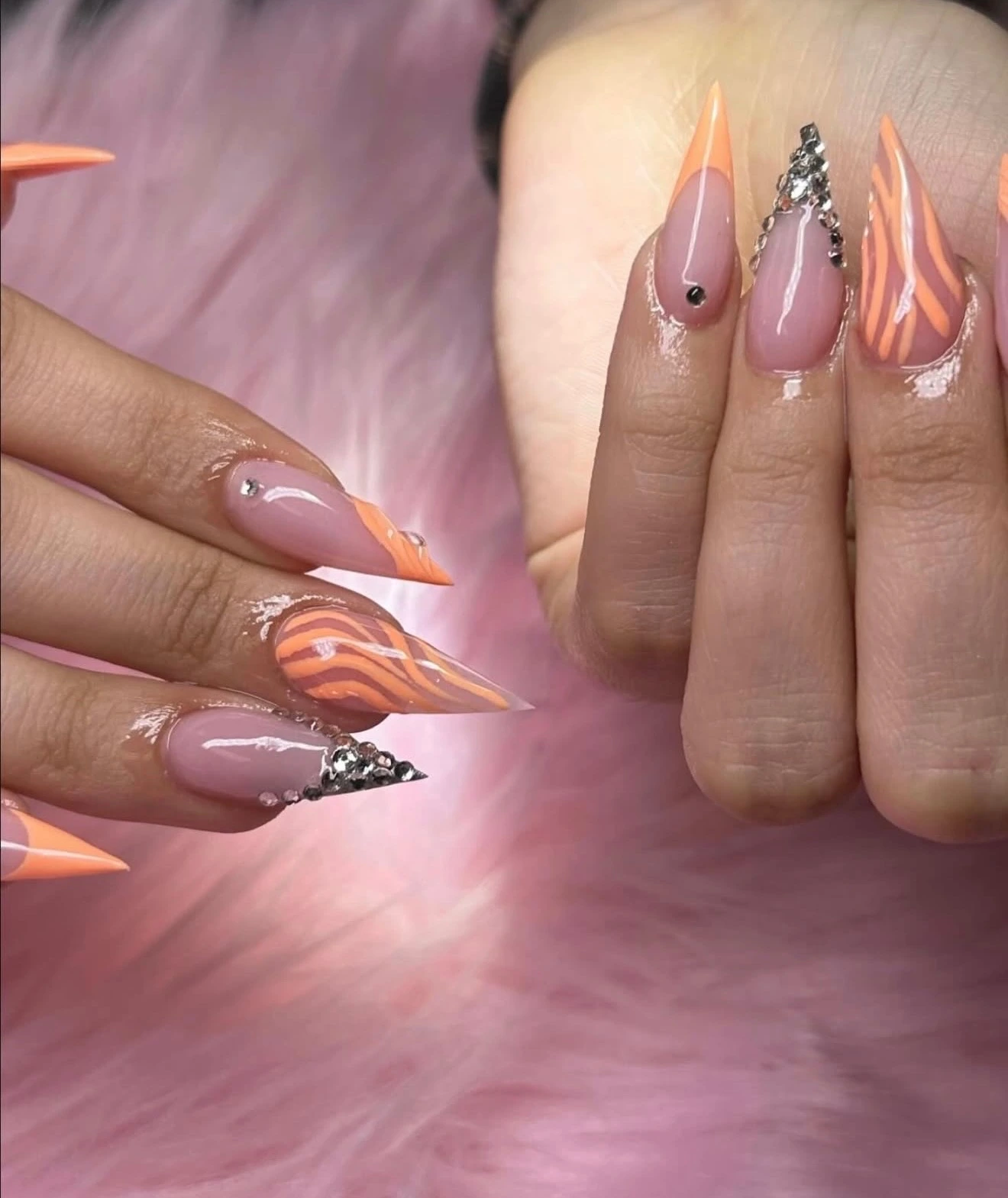 Peach-orange stiletto nails with striping and crystal accents
