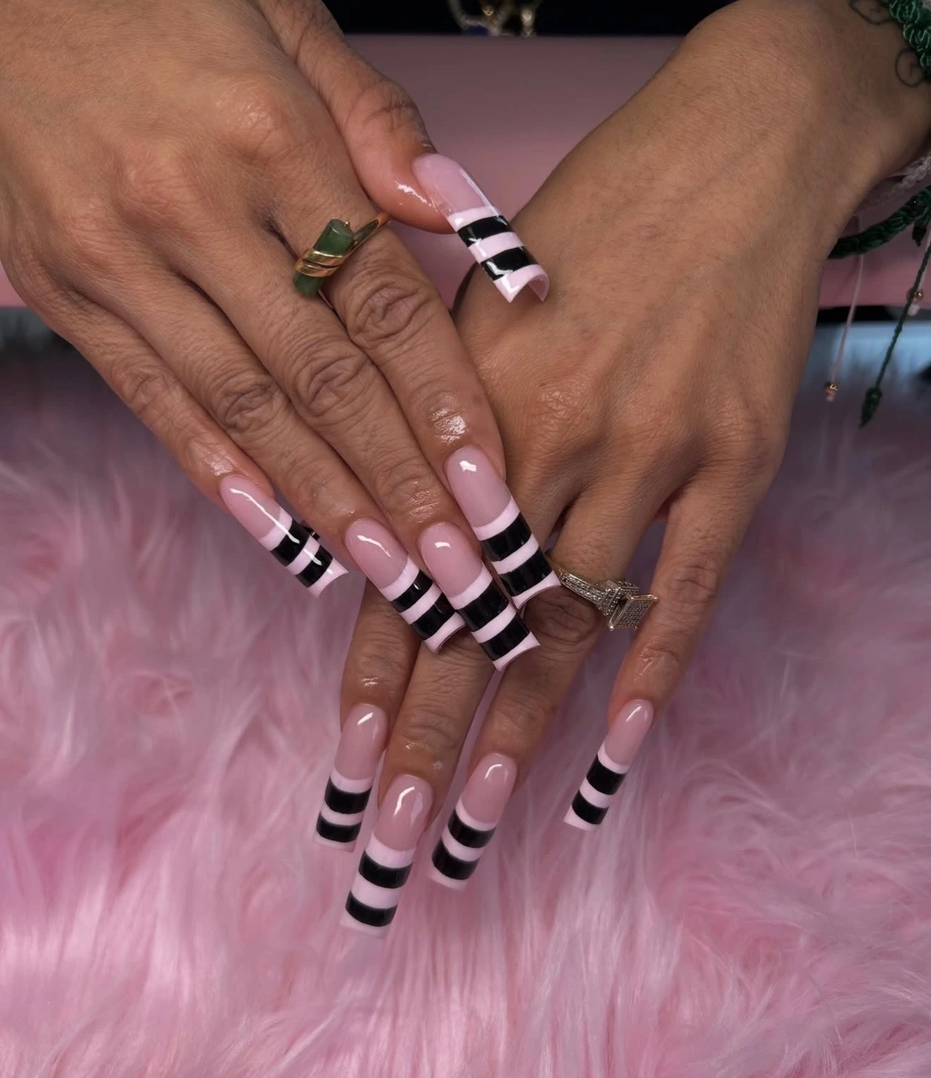 Long pink nails with bold black striped French tips