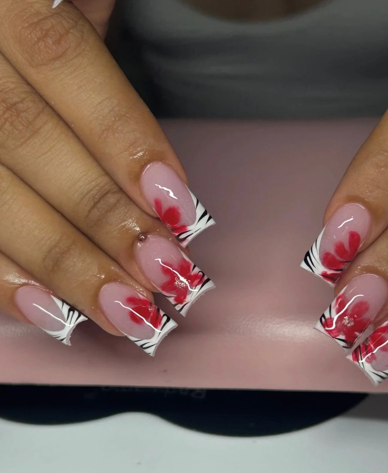 Red flowers painted over nude nails and graphic French tips